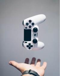 Podrzucony pad od ps4 w kolorze białym który spada do wyciągnietej dłoni
